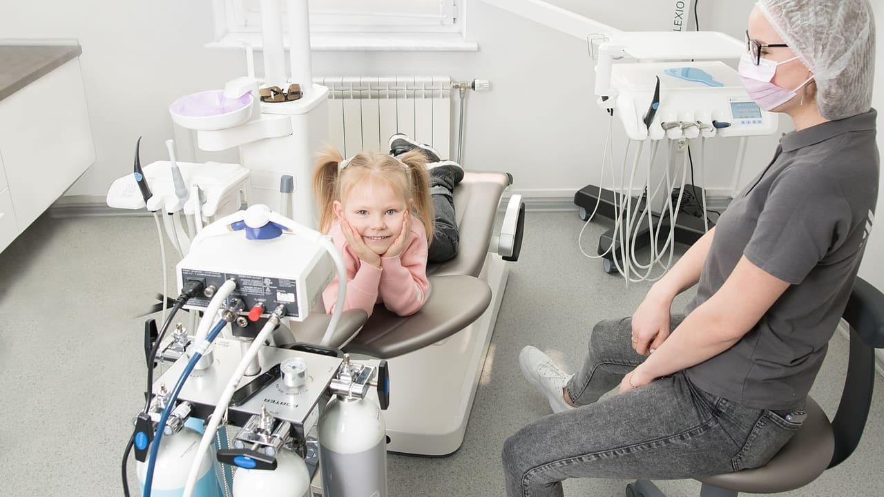 Niña sonriendo en un sillón dental, imagen de campaña