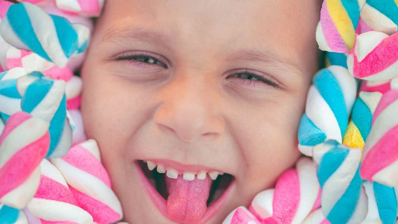 Niño sonriendo entre malvaviscos de colores