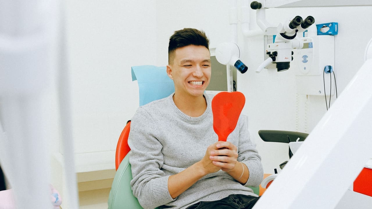 Joven observando su sonrisa en un espejo, imagen de campaña